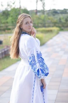 Portrait of young woman wearing blue national traditional embroidered shirt. pretty girl outdoor dressed in patriotic clothes.