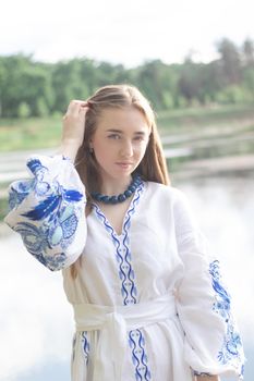 Portrait of young woman wearing blue national traditional embroidered shirt. pretty girl outdoor dressed in patriotic clothes.