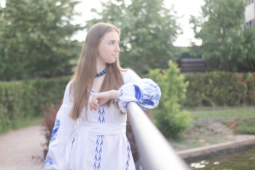 Portrait of young woman wearing blue national traditional embroidered shirt. pretty girl outdoor dressed in patriotic clothes.