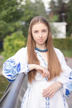 Portrait of young woman wearing blue national traditional embroidered shirt. pretty girl outdoor dressed in patriotic clothes.