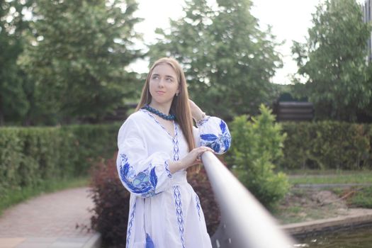 Portrait of young woman wearing blue national traditional embroidered shirt. pretty girl outdoor dressed in patriotic clothes.