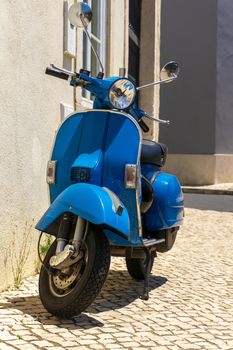 Bright blue moped parked on a European street close up