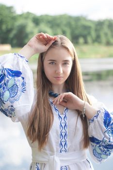 Portrait of young woman wearing blue national traditional embroidered shirt. pretty girl outdoor dressed in patriotic clothes.