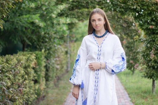 Portrait of young woman wearing blue national traditional embroidered shirt. pretty girl outdoor dressed in patriotic clothes.