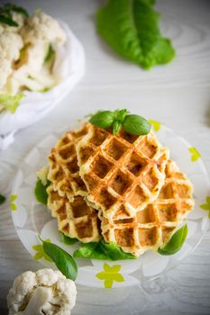 vegetable waffles cooked with cauliflower in a plate on a wooden table.