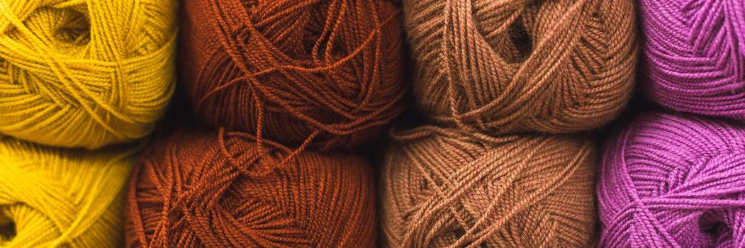Colored skeins of wool on a store shelf. Woolen skeins for knitting all the colors of the rainbow, brown, yellow, red and purple. Web banner.