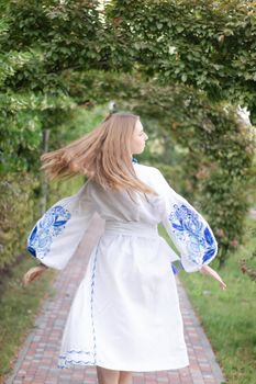 Portrait of young woman wearing blue national traditional embroidered shirt. pretty girl outdoor dressed in patriotic clothes.