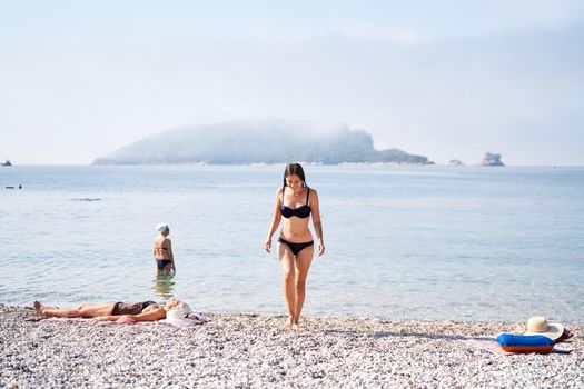 Young woman in a swimsuit comes out of the water on the beach. High quality photo