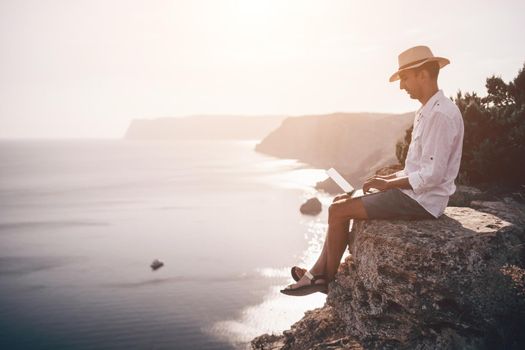 freelancer businessman working remotely on laptop at the beach near the sea