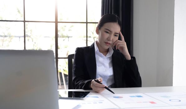 Image of an Asian woman who is tired and overthinking from working with a tablet at the office..