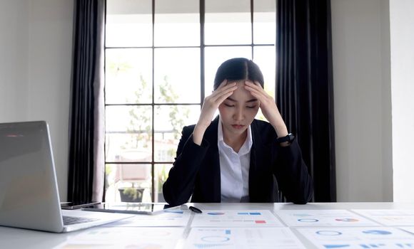 Young Asian businesswoman working on a tablet, is stressed has a headache and thinks hard at the office..