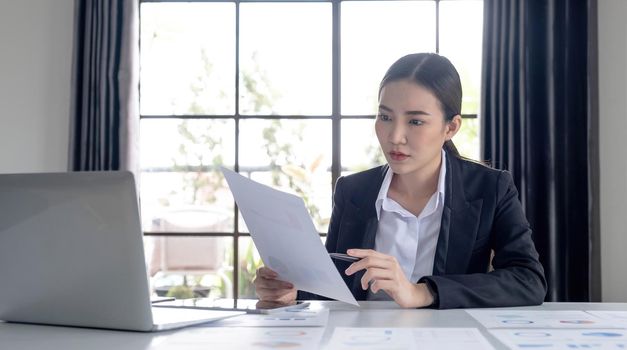 Portrait of an Asian woman working on a tablet computer in a modern office. Make an account analysis report. real estate investment information financial and tax system concepts.