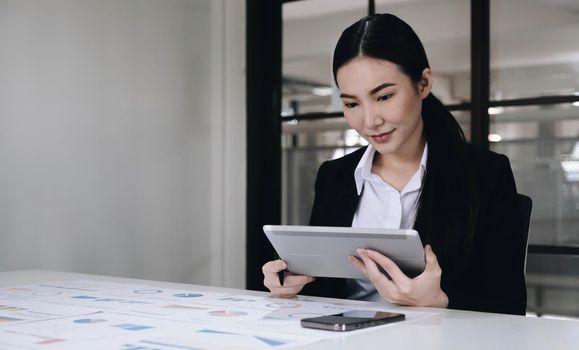 Young asian businesswoman works on tablet with laptop at the office..