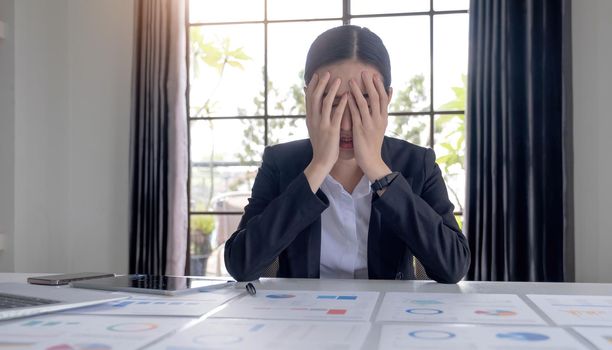 Young Asian businesswoman working on a tablet, is stressed has a headache and thinks hard at the office..