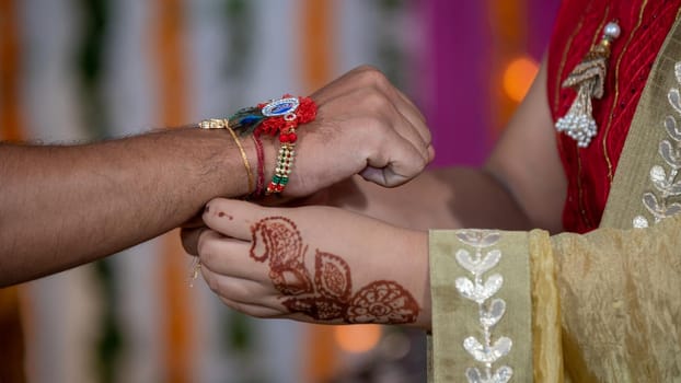 Sister tying the rakhi, Raksha Bandhan to brother's wrist during festival or ceremony - Raksha Bandhan celebrated across India as selfless love or relationship between brother and sister