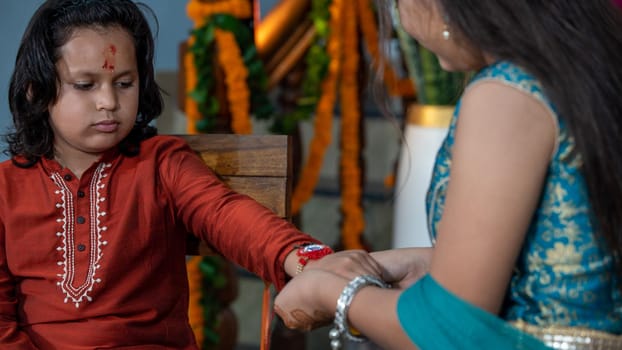Sister tying the rakhi, Raksha Bandhan to brother's wrist during festival or ceremony - Raksha Bandhan celebrated across India as selfless love or relationship between brother and sister