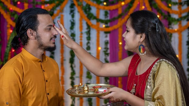 Indian families celebrating Raksha Bandhan festival a festival to celebrate the bond between brother and sister. Rakhi celebration in India. Feeding sweets, applying tikka.