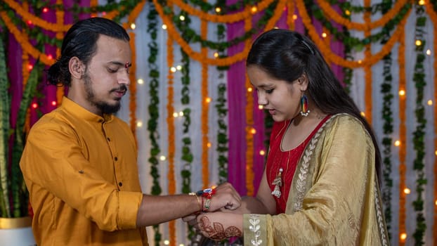 Sister tying the rakhi, Raksha Bandhan to brother's wrist during festival or ceremony - Raksha Bandhan celebrated across India as selfless love or relationship between brother and sister