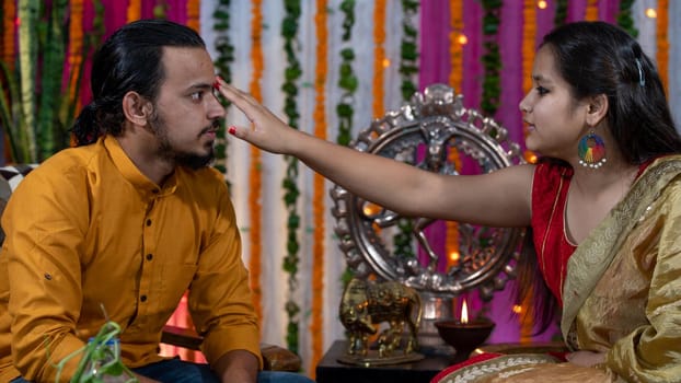 Indian families celebrating Raksha Bandhan festival a festival to celebrate the bond between brother and sister. Rakhi celebration in India. Feeding sweets, applying tikka.