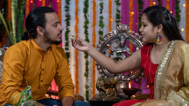 Indian families celebrating Raksha Bandhan festival a festival to celebrate the bond between brother and sister. Rakhi celebration in India. Feeding sweets, applying tikka.