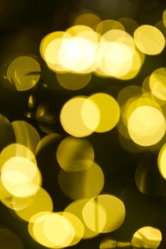 blurred christmas lights abstract background on dark backdrop. Yellow Circular reflections of Christmas lights.