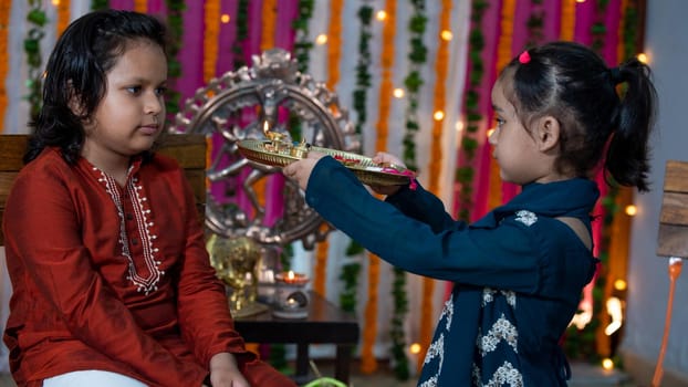 Indian families celebrating Raksha Bandhan festival a festival to celebrate the bond between brother and sister. Rakhi celebration in India. Feeding sweets, applying tikka.