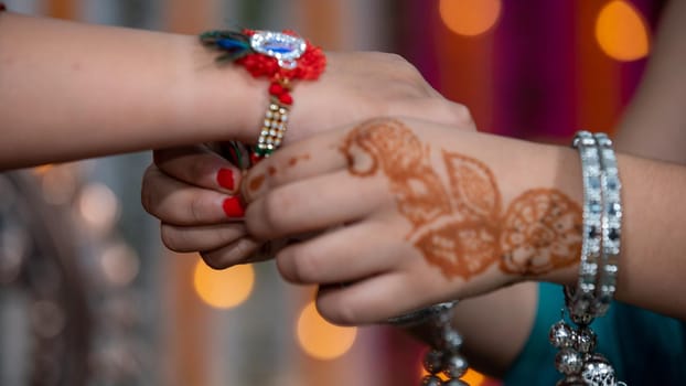 Sister tying the rakhi, Raksha Bandhan to brother's wrist during festival or ceremony - Raksha Bandhan celebrated across India as selfless love or relationship between brother and sister