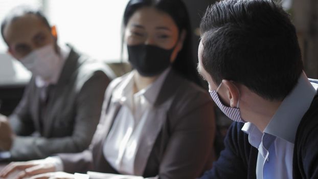 Teamwork Of Multi-Ethnic Business Group In Office During Quarantine, Business People Forced To Work In Protective Masks In Connection With Epidemic Of Coronavirus, Selective Focus Man In Foreground