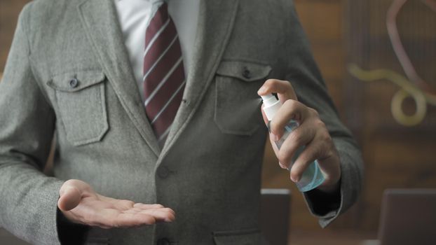 Business Man's Hands Holding And Using Sanitizer Spray, Businessman In Grey Suit Demonstrating Of Sanitizer Spray Work, Front View, Close Up Shot