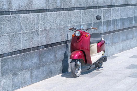 a red scooter standing against a stone wall. High quality photo