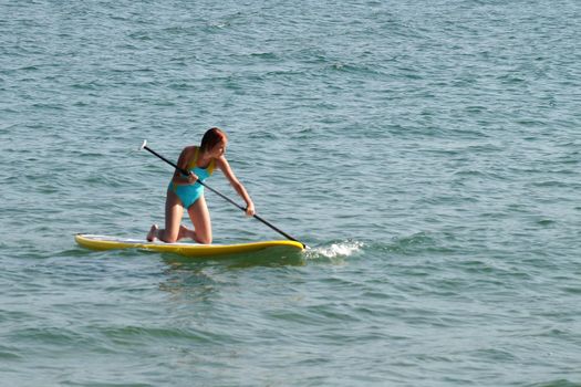 a teenage girl rowing an oar on a SUP-board