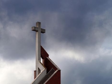 Catholic cross on the temple against the backdrop of a stormy dark sky, copy space