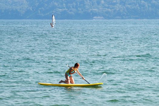 teenage girl riding a supboard in the sea on her knees.