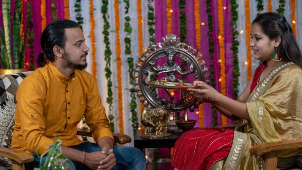 Indian families celebrating Raksha Bandhan festival a festival to celebrate the bond between brother and sister. Rakhi celebration in India. Feeding sweets, applying tikka.