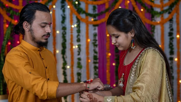 Sister tying the rakhi, Raksha Bandhan to brother's wrist during festival or ceremony - Raksha Bandhan celebrated across India as selfless love or relationship between brother and sister