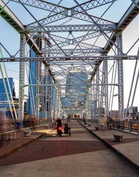 Tourists on the John Seigenthaler pedestrian bridge or Shelby street crossing leaving downtown Nashville Tennessee