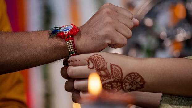 Sister tying the rakhi, Raksha Bandhan to brother's wrist during festival or ceremony - Raksha Bandhan celebrated across India as selfless love or relationship between brother and sister