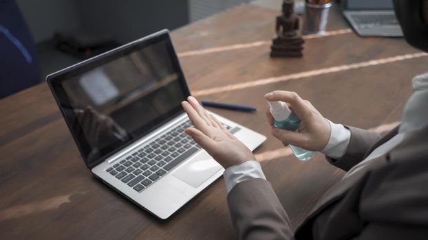 Oriental Woman Uses Hand Sanitizer Spray Before Working With Computer, Businesswoman Is Applying Spray To Disinfect Her Hands Using Laptop, High Angle View