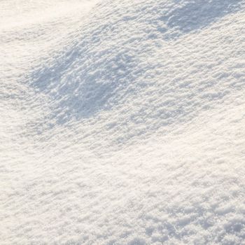 Hilly surface covered with fresh snow in the garden on a sunny day. Natural winter background.