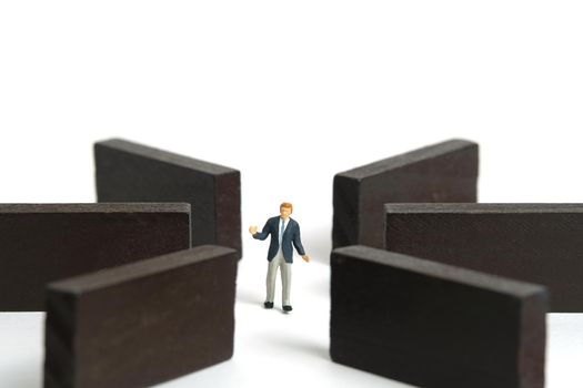 Miniature people toy figure photography. Strategy choice concept. A shrugging businessman standing in the middle of wooden maze labyrinth. Isolated on white background. Image photo