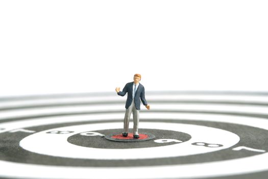 Miniature people toy figure photography. A shrugging businessman standing the center of dartboard. Isolated on white background. Image photo