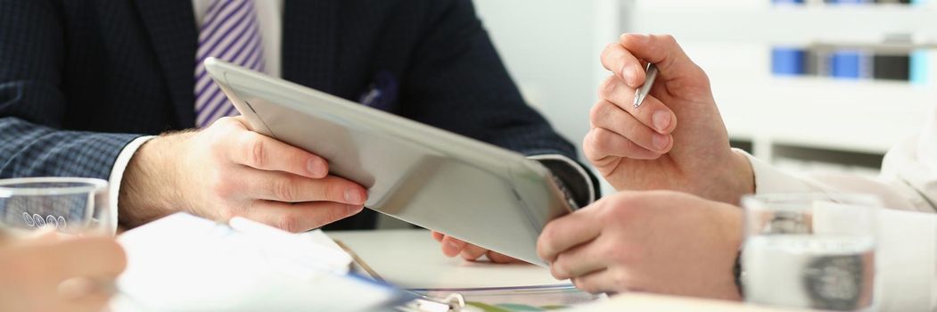 Close-up of manager holding special pen and paper tablet with document to sign. Discussing contract that determine corporation future. Strategy concept