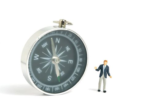 Miniature people toy figure photography. Business direction concept. A shrugging businessman stand above a black compass. Isolated on white background. Image photo