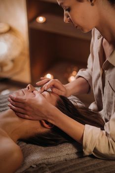 A cosmetologist girl does a facial and neck massage to a girl in the office for skin elasticity.