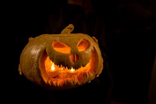 The witch is holding a pumpkin jack about a lantern glowing in the dark. Halloween