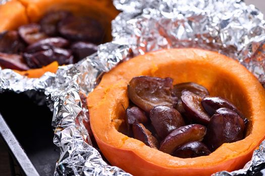 Hokkaido pumpkin halves baked in foil stuffed with plums on a baking sheet. Vegetarian food. The ketogenic diet. Vegan paleo