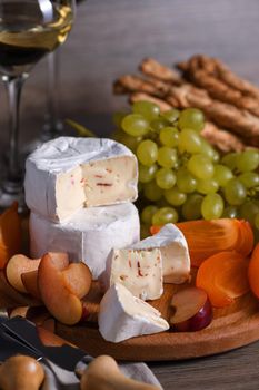 Cheese camembert with white grapes, sliced persimmons and plums, a great appetizer for wine 