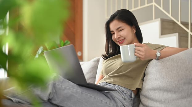 Joyful young woman browsing internet, chatting with friends on laptop computer.