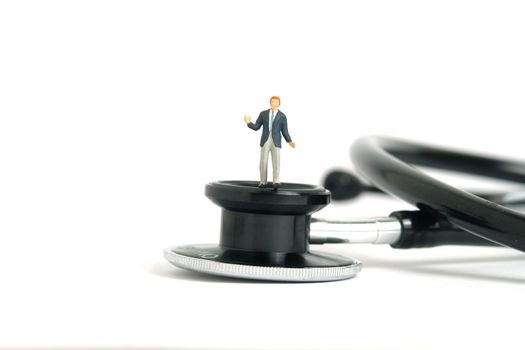 Miniature people toy figure photography. Hesitation on medical check exam concept. A shrugging businessman standing above stethoscope. Isolated on white background. Image photo