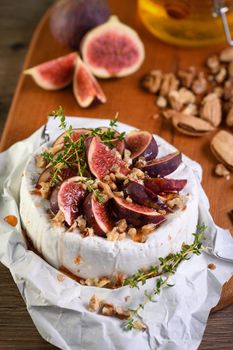 Brie cheese served on a wooden board with figs, walnuts and honey